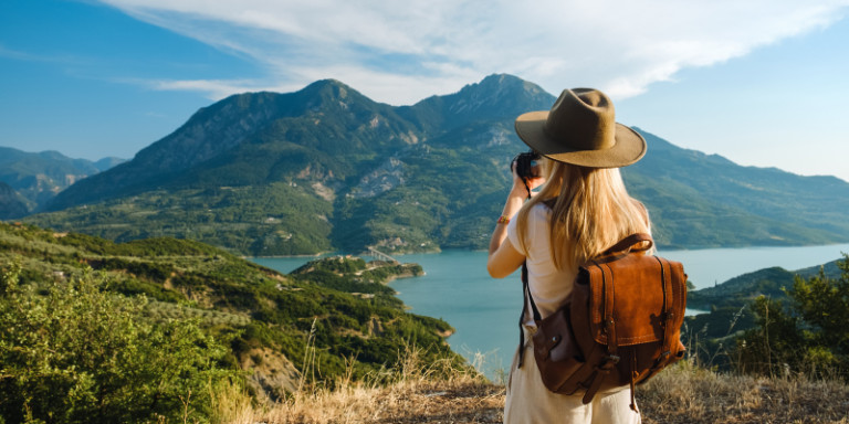 Frau mit Hut fotografiert eine Landschaft